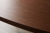 Close-up of the walnut veneer on the Rossano table: fine grain in a dark reddish brown running to the thin bevelled edge of the top