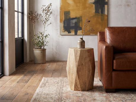 Rotondella Faceted Mango Drum Side Table beside a leather sofa in an industrial loft