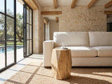 Rotondella Faceted Mango Drum Side Table beside a linen sofa in a poolside villa