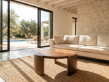 Rovereto Brown Ash Veneer Round Coffee Table on a jute rug in front of a linen sofa in a poolside villa