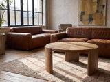 Rovereto Brown Ash Veneer Round Coffee Table on a vintage rug in front of a leather sofa in an industrial loft