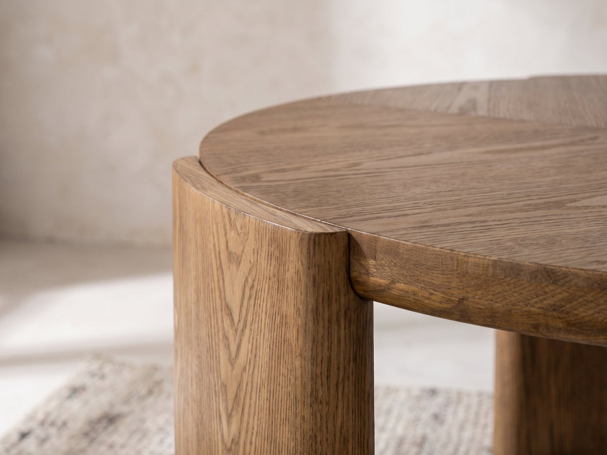 Close-up of the Rovereto Brown Ash Veneer Round Coffee Table: a curved ash leg wrapping the edge of the round top