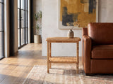 Rutigliano Braided Rattan Two-Tier Side Table beside a cognac leather armchair in an industrial loft