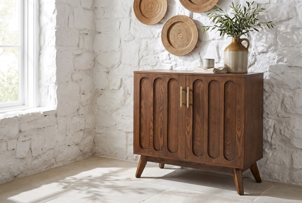 Ruvo walnut-finish accent cabinet with an olive-branch jug on top against a whitewashed stone wall in a Napa Valley dining room, limestone floor and a sunny window