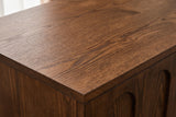 Close-up of the walnut finish on the Ruvo cabinet: open wood grain across the top, running to a square edge above a raised panel