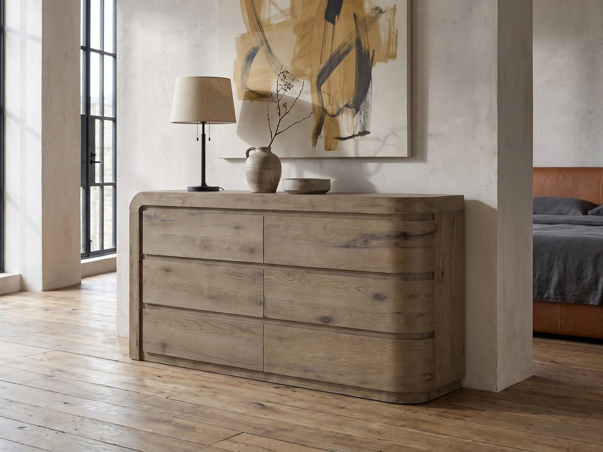 Sacile 70-Inch Weathered Natural Oak 6-Drawer Dresser against a plaster wall in an industrial loft bedroom