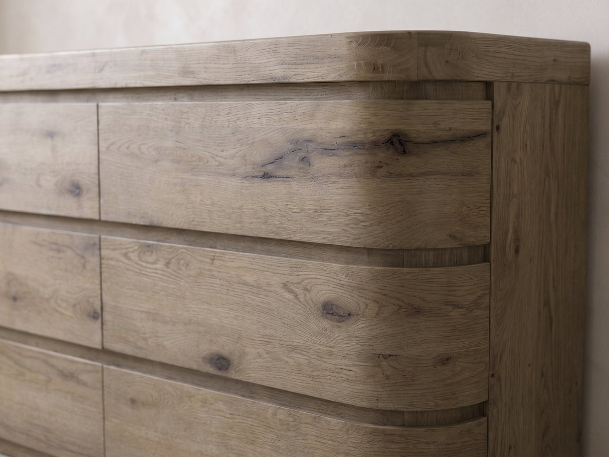 Close-up of the Sacile 70-Inch Weathered Natural Oak 6-Drawer Dresser: the right-hand drawer fronts bending around the rounded corner, in knotty oak veneer