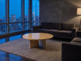 Salina Gold Beige Marble Coffee Table on a wool rug in front of a velvet sofa in a city penthouse at blue hour