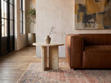 Salina Gold Beige Marble Round Side Table beside a leather sofa in an industrial loft