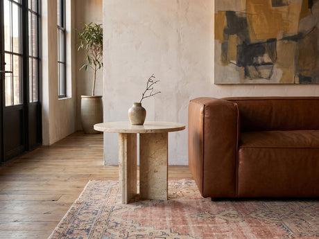 Salina Gold Beige Marble Round Side Table beside a leather sofa in an industrial loft