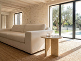 Salina Gold Beige Marble Round Side Table beside a linen sofa in a poolside villa