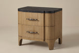 The Samassi two-drawer nightstand in honey-tan eucalyptus veneer with a black stone top, three-quarter view on a light studio backdrop