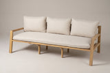The Sambuca slim-arm acacia outdoor sofa with one long beige seat cushion and three back cushions, three-quarter view on a light studio backdrop