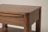 The top corner of the Sanluri nightstand: the rounded top flowing into the rounded front post, and the thin lip with a carved recess along the top drawer