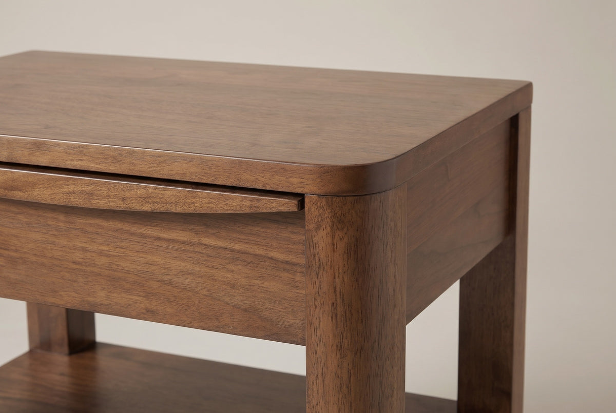 The top corner of the Sanluri nightstand: the rounded top flowing into the rounded front post, and the thin lip with a carved recess along the top drawer