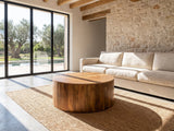 Sansepolcro Natural Mango Drum Coffee Table on a jute rug in front of a linen sofa in a poolside villa
