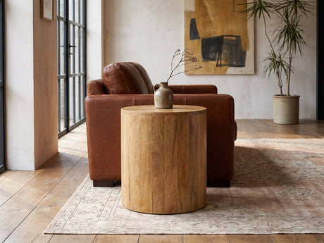 Sansepolcro Natural Mango Drum Side Table beside a cognac leather armchair in an industrial loft