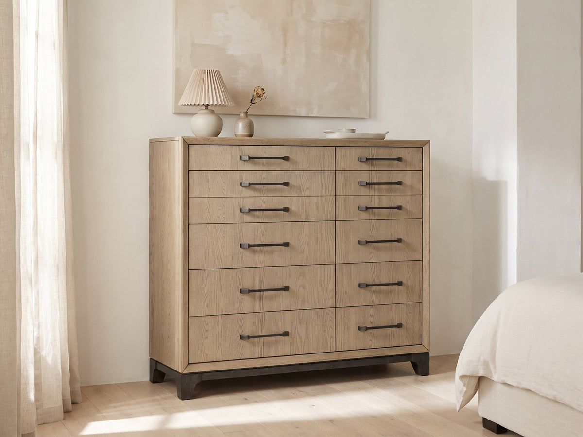 Sappada 54-Inch Caramel Oak and Cocoa 12-Drawer Chest against a plaster wall under an abstract canvas in a bright bedroom