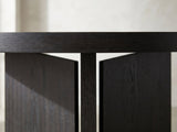 Close-up of the Saracena 54-Inch Round Ebony Oak Dining Set with 4 Boucle Chairs: the thick edge of the ebony oak top over the slab blades of the pedestal