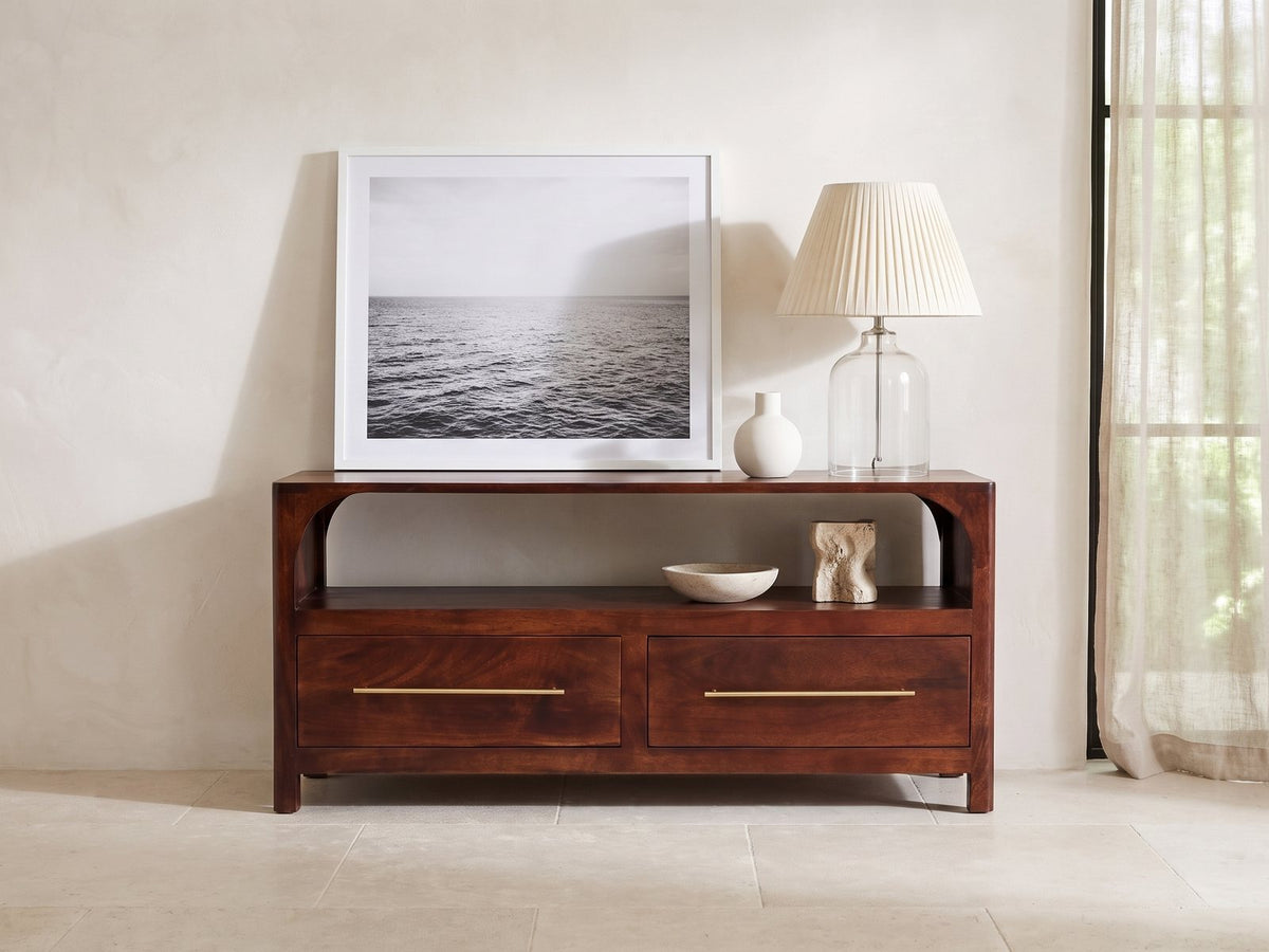Sarzana 47-Inch Winewood Solid Mango Arched Media Console styled with a leaning print, a lamp and ceramics in a bright plaster room