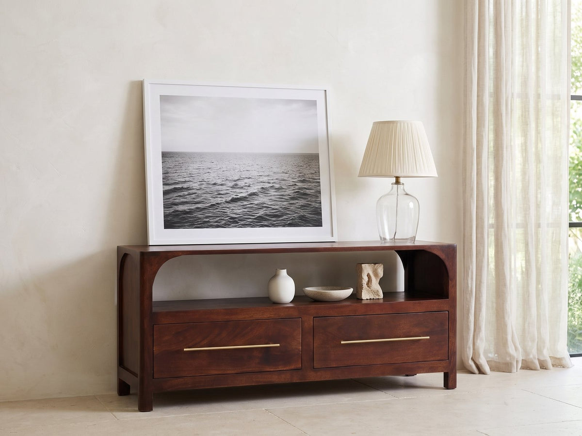 Sarzana 47-Inch Winewood Solid Mango Arched Media Console seen from the side, styled with a leaning print, a lamp and ceramics in a bright plaster room