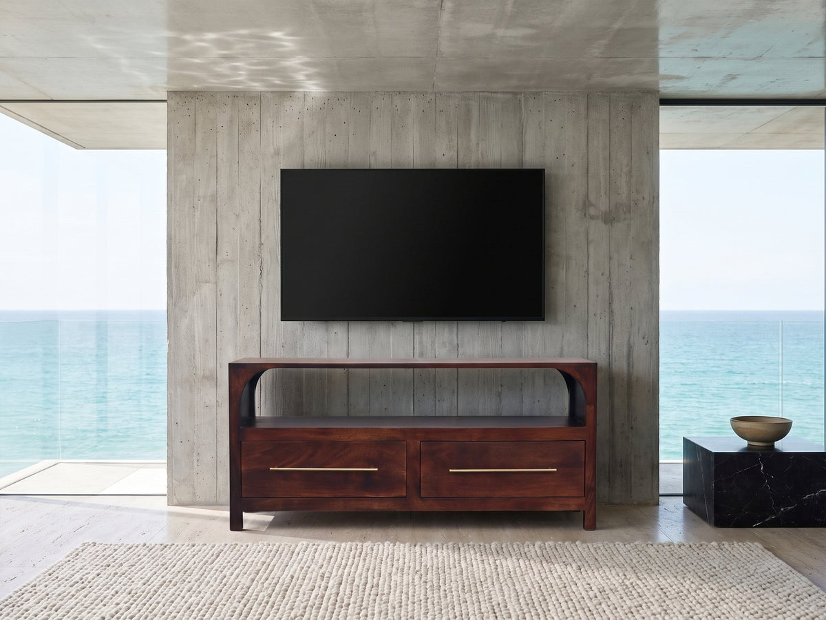 Sarzana 47-Inch Winewood Solid Mango Arched Media Console under a wall-mounted screen in an oceanfront glass house