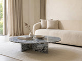 Saturnia Blue-Grey Marble Coffee Table styled with books, a vase and a stone bowl in front of a cream sofa in a bright plaster room