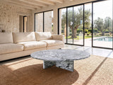 Saturnia Blue-Grey Marble Coffee Table seen from the side, on a jute rug in front of a linen sofa in a poolside villa