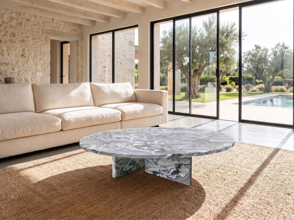 Saturnia Blue-Grey Marble Coffee Table seen from the side, on a jute rug in front of a linen sofa in a poolside villa