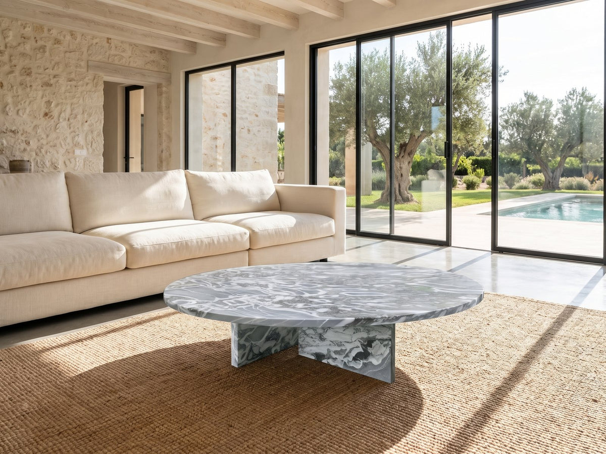 Saturnia Blue-Grey Marble Coffee Table on a jute rug in front of a linen sofa in a poolside villa
