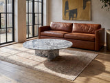 Saturnia Blue-Grey Marble Coffee Table on a vintage rug in front of a leather sofa in an industrial loft
