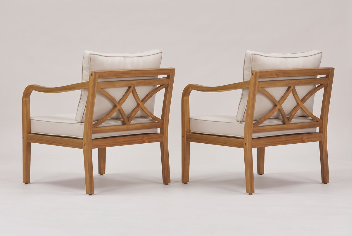 The two Savoca chairs seen from behind: the cross-back panels of bowed acacia bars, the beige back pillows and the curved arms