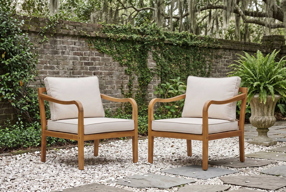 Two Savoca acacia club chairs on white oyster-shell gravel in a Savannah walled garden, an old brick wall with creeping fig and live oaks behind (urn and fern not included)