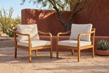 Two Savoca acacia club chairs on sandstone flagstones in front of a terracotta adobe wall in a Tucson desert patio, a mesquite tree behind (planter not included)