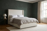 Scanno ivory canvas wingback bed against a deep green plaster wall in a Boston townhouse bedroom with a sash window and a cream wool rug