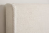 Close-up of the Scanno headboard in ivory canvas: the rounded top of a slim wing beside the flat panel