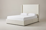 The Scanno ivory canvas wingback bed with a tall flat headboard, two slim wings, a deep base, a white mattress and pillows (not included), three-quarter view on a light studio backdrop