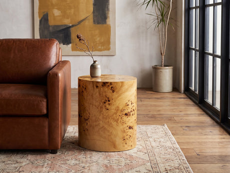 Scapoli Burl Veneer Oval Pillar Side Table beside a leather sofa in an industrial loft