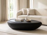 Scicli Black Fiberglass Pebble Coffee Table styled with books, a vase and a stone bowl in front of a cream sofa in a bright plaster room