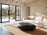 Scicli Black Fiberglass Pebble Coffee Table on a jute rug in front of a linen sofa in a poolside villa