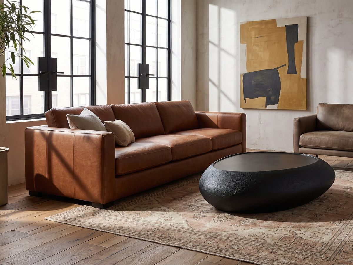 Scicli Black Fiberglass Pebble Coffee Table on a vintage rug in front of a leather sofa in an industrial loft