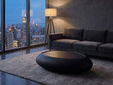 Scicli Black Fiberglass Pebble Coffee Table on a wool rug in front of a velvet sofa in a city penthouse at blue hour