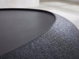 Close-up of the Scicli Black Fiberglass Pebble Coffee Table: the textured black rim around the smooth charcoal top