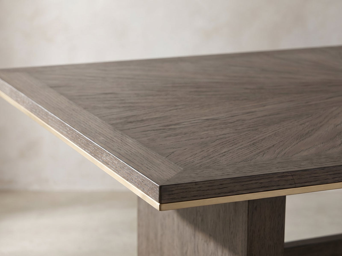 Close-up of the Scilla 75.5 to 95.5-Inch Sunburst Oak Extending Dining Set with 4 Armchairs: the sunburst oak veneer top and its thin gold-finish edge band