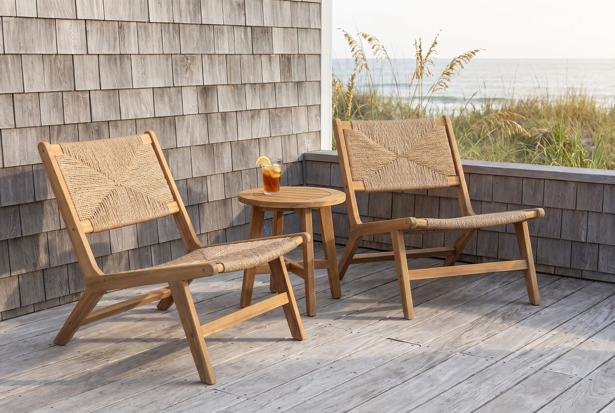Two Scopello acacia and wicker lounge chairs on a grey weathered deck beside a Carolina coast cedar-shingle wall, with sea oats and the ocean beyond (side table and drink not included)