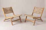The set of two Scopello acacia and wicker lounge chairs, three-quarter view from the front on a light studio backdrop