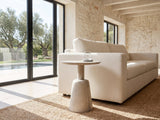 Segesta Whitewashed Mango Pedestal Side Table beside a linen sofa in a poolside villa