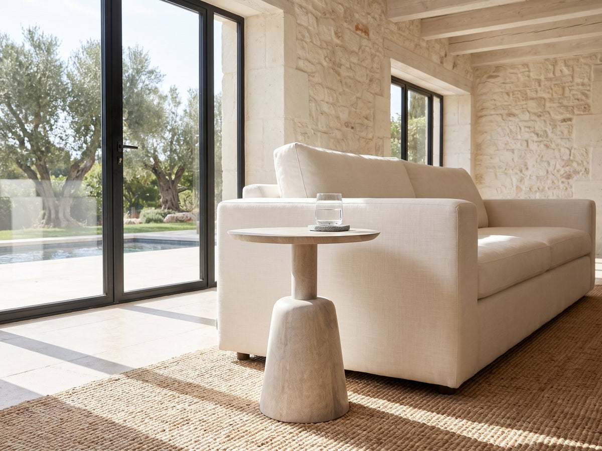 Segesta Whitewashed Mango Pedestal Side Table beside a linen sofa in a poolside villa
