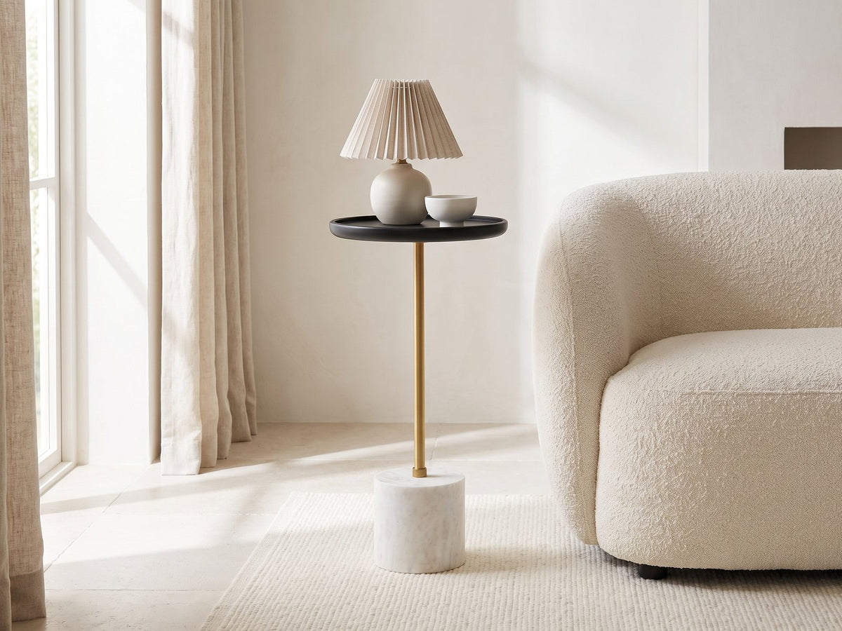 Seggiano Black Mango and Marble Drink Side Table with a lamp and a ceramic bowl beside a cream boucle armchair in a bright plaster room