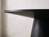 Close-up of the Sellia 59-Inch Round Ebony Cone Pedestal Dining Set with 4 Chairs: the slim edge and sloped underside of the round top over the cone pedestal